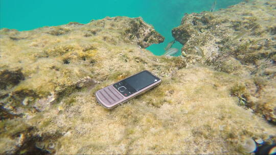 人捡起掉在海底珊瑚礁上的手机