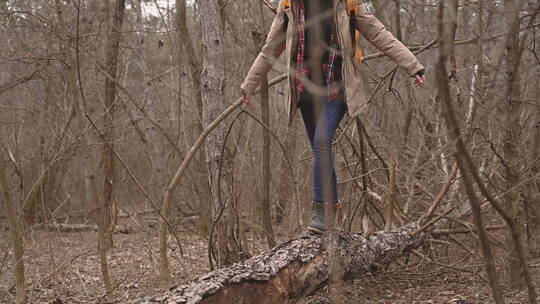 森林里倒下树木上行走的女孩