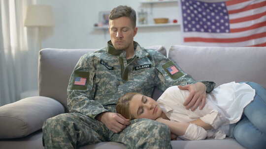 心烦意乱的美国士兵抚摸睡在沙发上的女朋友，兵役视频素材模板下载