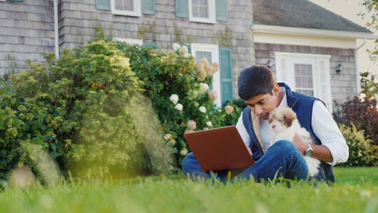 男孩抱着小狗坐在户外学习