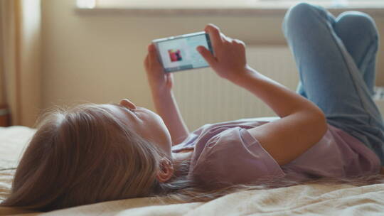 女孩躺在床上看手机视频素材模板下载