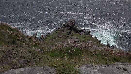 游客爬上海边的悬崖