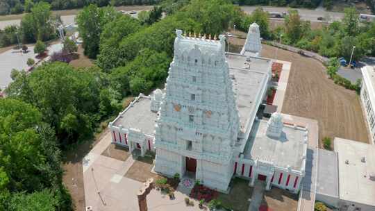 白天，无人机在路边旋转拍摄白色印度教南印度寺庙。