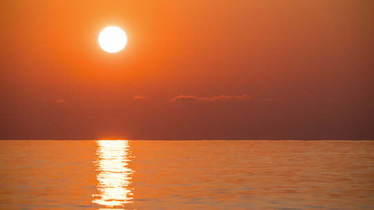 海上大红日日落的延时。橙色阳光路径与海面反射