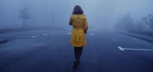 女孩走在大雾弥漫的马路上