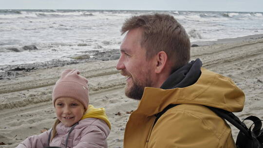 爸爸带着女儿在海边玩