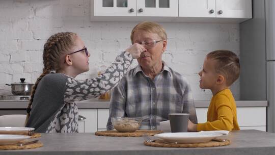 孙辈们在早餐时帮助祖母