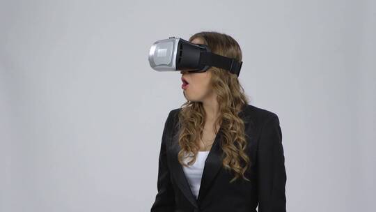 女人在灰色背景上戴着虚拟现实眼镜