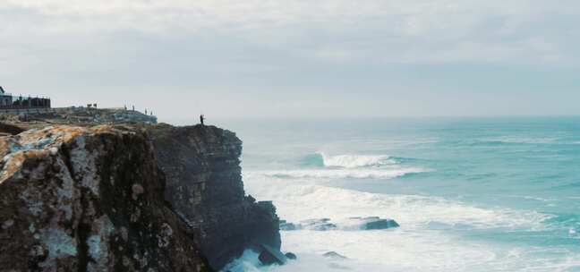 渔夫站在海边的悬崖上投掷绳索