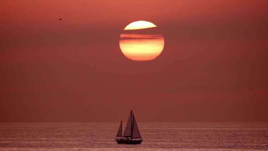 4k帆船在海面前行日落下山