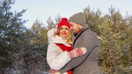 穿着冬装的夫妇在雪域森林拥抱视频素材模板下载