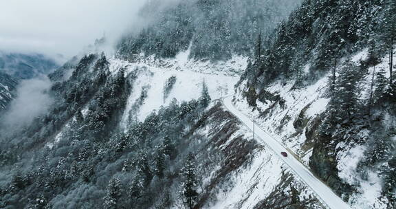 航拍自驾游汽车行驶在白雪皑皑的盘山路上