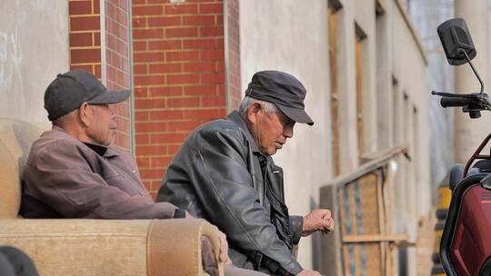 农村老人坐在路边晒太阳抽烟闲聊