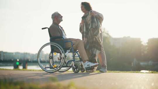 妻子扶丈夫坐轮椅女人盖着毯子一起走的老人