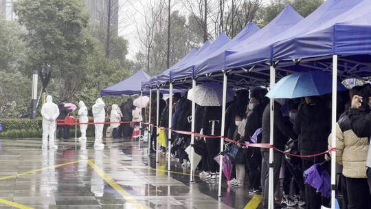 下雨天市民排队在城市广场上做核酸