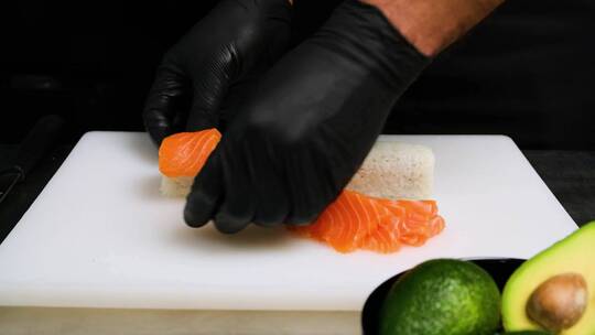 把鲑鱼片放在寿司上。在家厨房做寿司视频素材模板下载