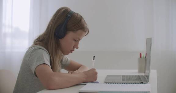 女孩在家里用笔记电脑坐家庭作业