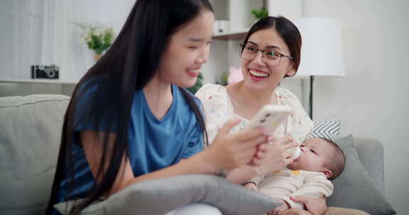 两个年轻的亚洲女人在家里开心地和一个婴儿