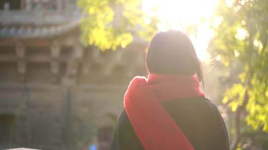 一个戴红色围巾的女人站在阳光下看远方背影视频素材模板下载