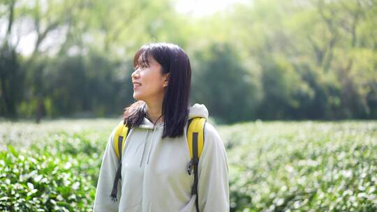 春天年轻女孩郊游茶园背包走路穿过清新茶树