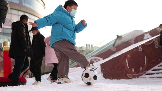 小孩子在雪地里玩耍踢足球