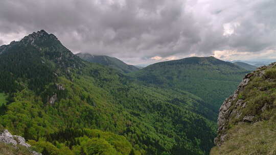 春天大自然中绿色森林山脉上空戏剧性的灰色云彩
