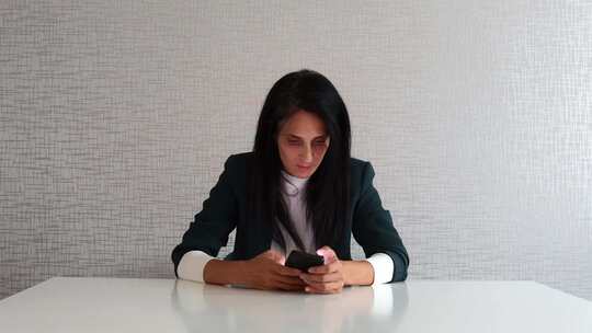 女人坐在办公室使用电话发短信