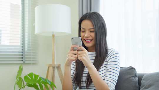 坐在沙发上用手机聊天的女性