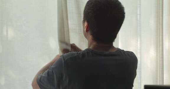 男人在家放松身心拉开窗帘眺望窗外