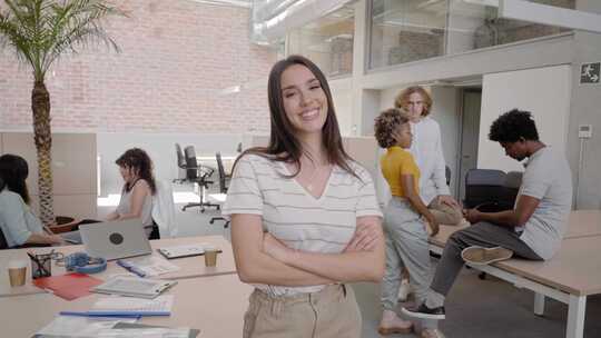 一个漂亮的年轻女商人在拥挤的办公室里看着