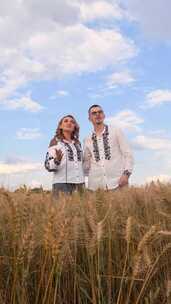 一对幸福的夫妇站在麦田里，在多云的天空下