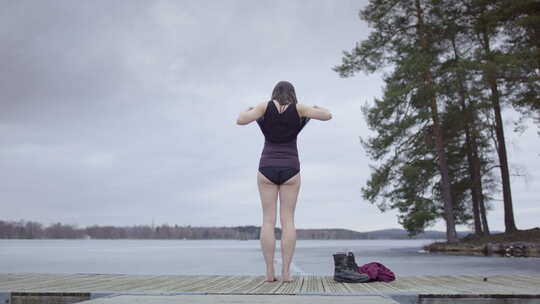 一名妇女在瑞典湖中脱下衣服准备冰浴，滑梯