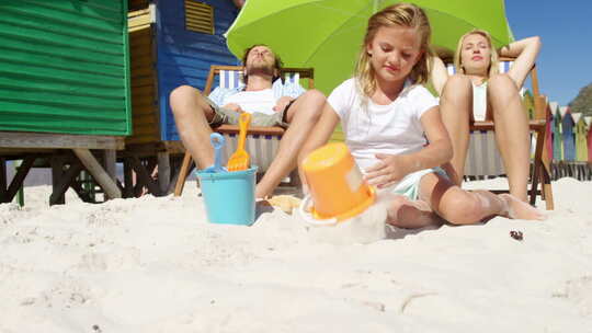 家庭在海滩放松时，女孩玩沙子视频素材模板下载