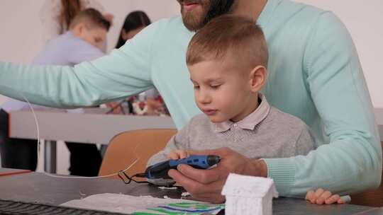 一位父亲和他的小儿子在学校用3D笔制作3