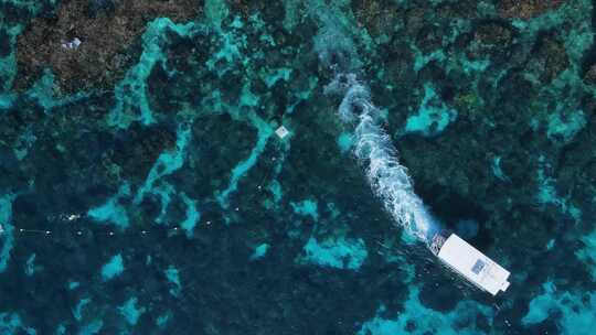 潜水船在热带珊瑚礁系统上空穿过水面的独特景色。高无人机视图视频素材模板下载