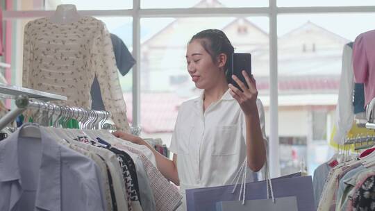 女子在服装店购物歌亲朋好友视频电话打招呼