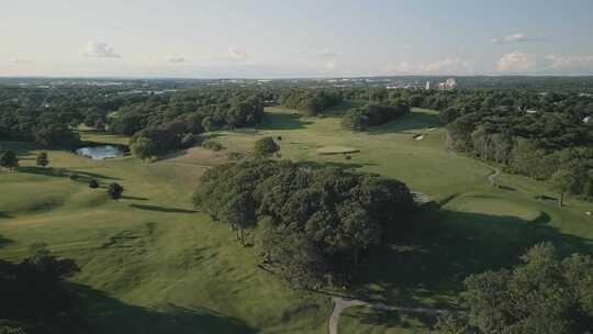 美丽日落时高尔夫球场上绿草和树木的鸟瞰图