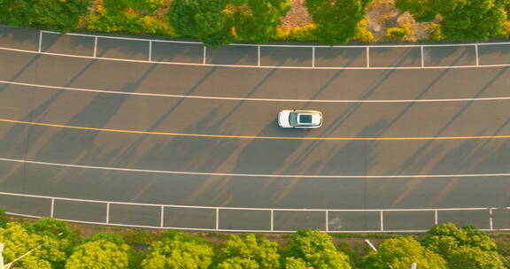 夕阳下白色车行驶在公路航拍