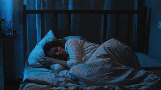 失眠晚上睡不安稳年轻女子辗转反侧躺在床上