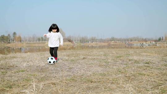 冬季在公园草坪上踢球的中国女孩