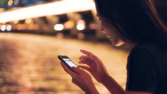 女孩夜晚在江边玩手机4k视频素材