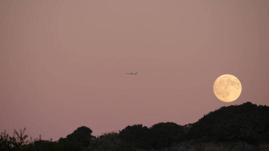 一架飞机在空中飞过明月