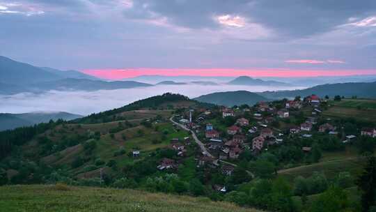 山坡上的日出景色和晨雾和一个小村庄