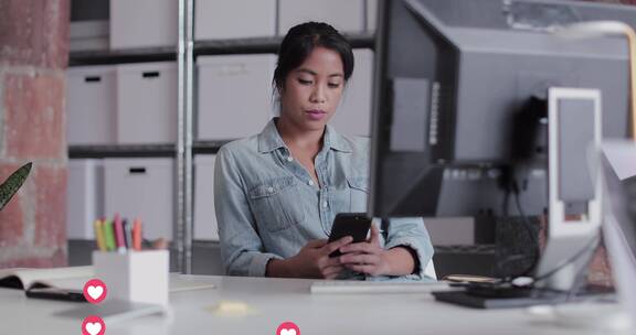 女人坐在电脑前使用手机
