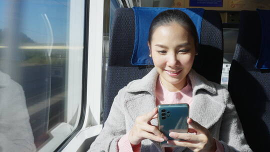 开心微笑的女性在高铁旅行中使用手机