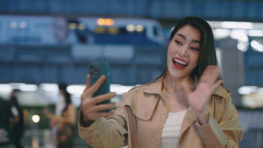 迷人的亚洲女孩使用手机进行视频通话站在夜