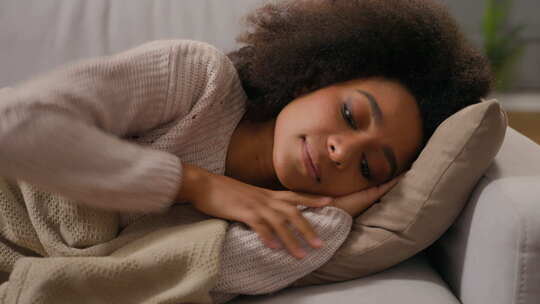 年轻的非裔美国妇女白天盖着毯子放松睡觉的