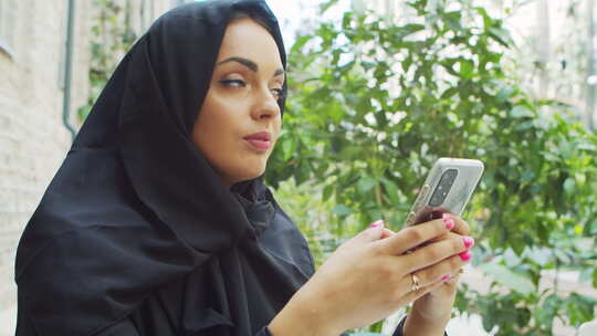 头巾中东年轻自信的穆斯林女商人手持智能手视频素材模板下载