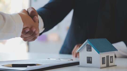 商务人士握手 房产模型置于桌上