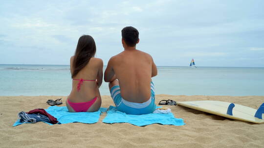 坐在海滩上的年轻夫妇后视图